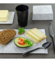Frühstückstisch mit schwarzem Holzbecher, weißer Butterdose und dekoriertem Marmorteller