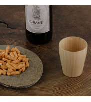 Small wooden mug in nature with stone plate filled with snacks and wine bottle