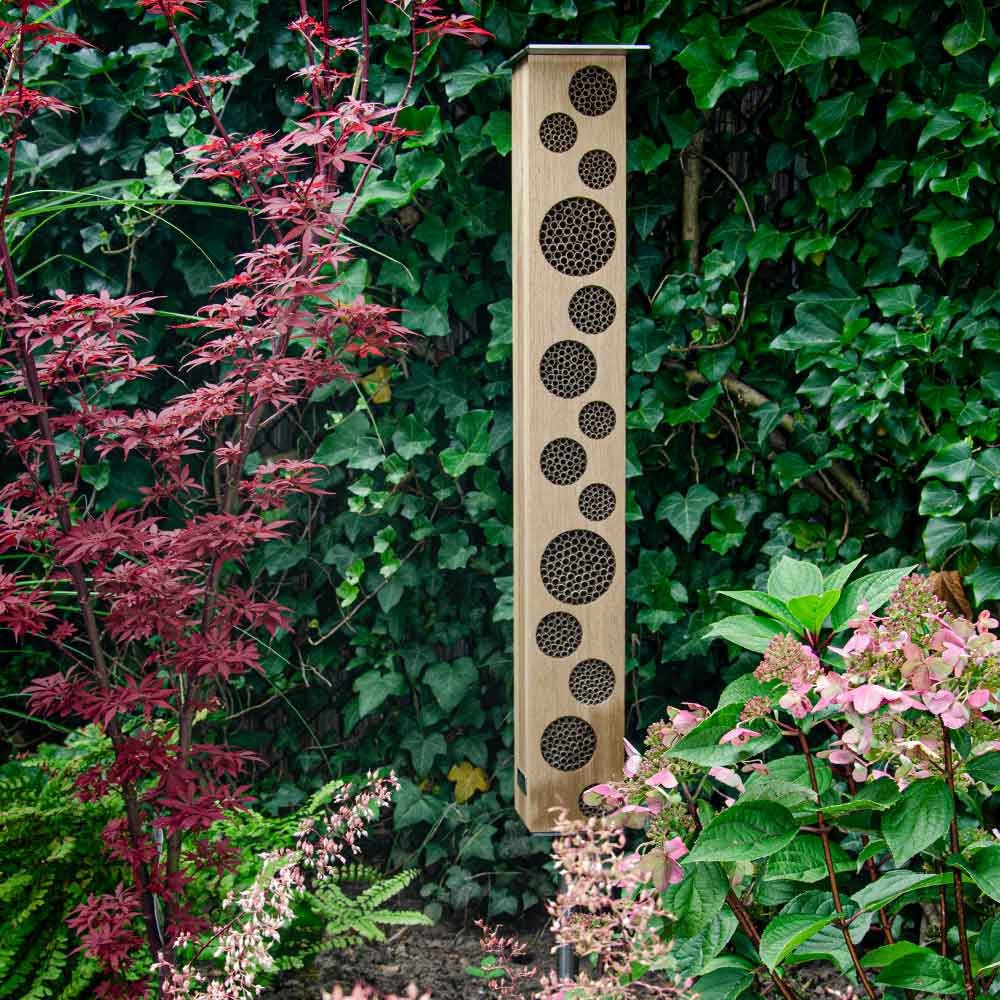 Bienen-Hochhaus BEE TOWER 80 aus Eiche natur mit Nisthülsen in Ausfräsungen, stehend auf Erdspieß im Garten