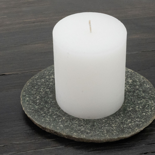 RIVA-S candle plate made of river stone in stone gray with white pillar candle on bog oak plate